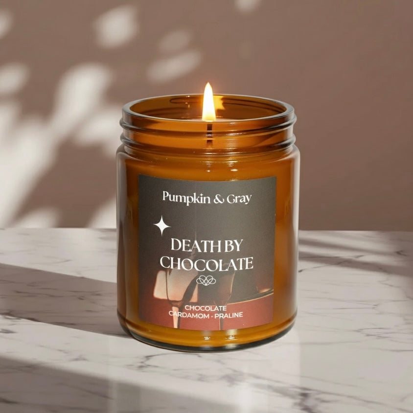 Candle in a glass jar labeled 'Death by Chocolate' from Pumpkin & Gray on a marble surface.