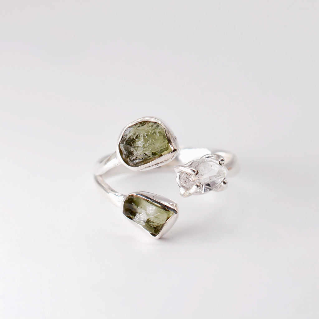 Three silver rings with green and clear gemstones on a white background