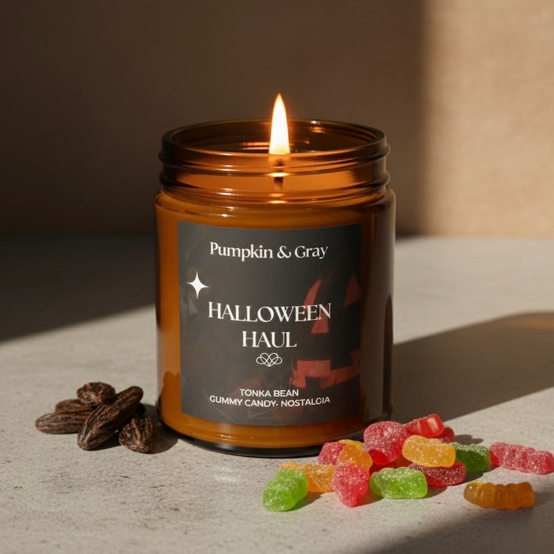 Candle in a jar labeled 'Pumpkin & Gray' with Halloween-themed gummy candies and dried fruits on a neutral background.