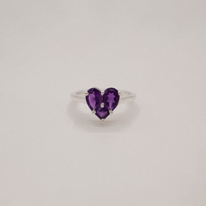 Heart-shaped purple gemstone ring on a light gray background